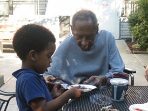 Idalio (98) cutting up a piece of his chocolate birthday cake for Michael (4)